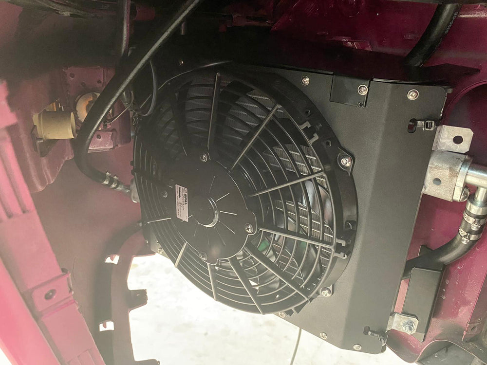 An electric air conditioning system condenser and fan in the front wheel arch of a Porsche sports car