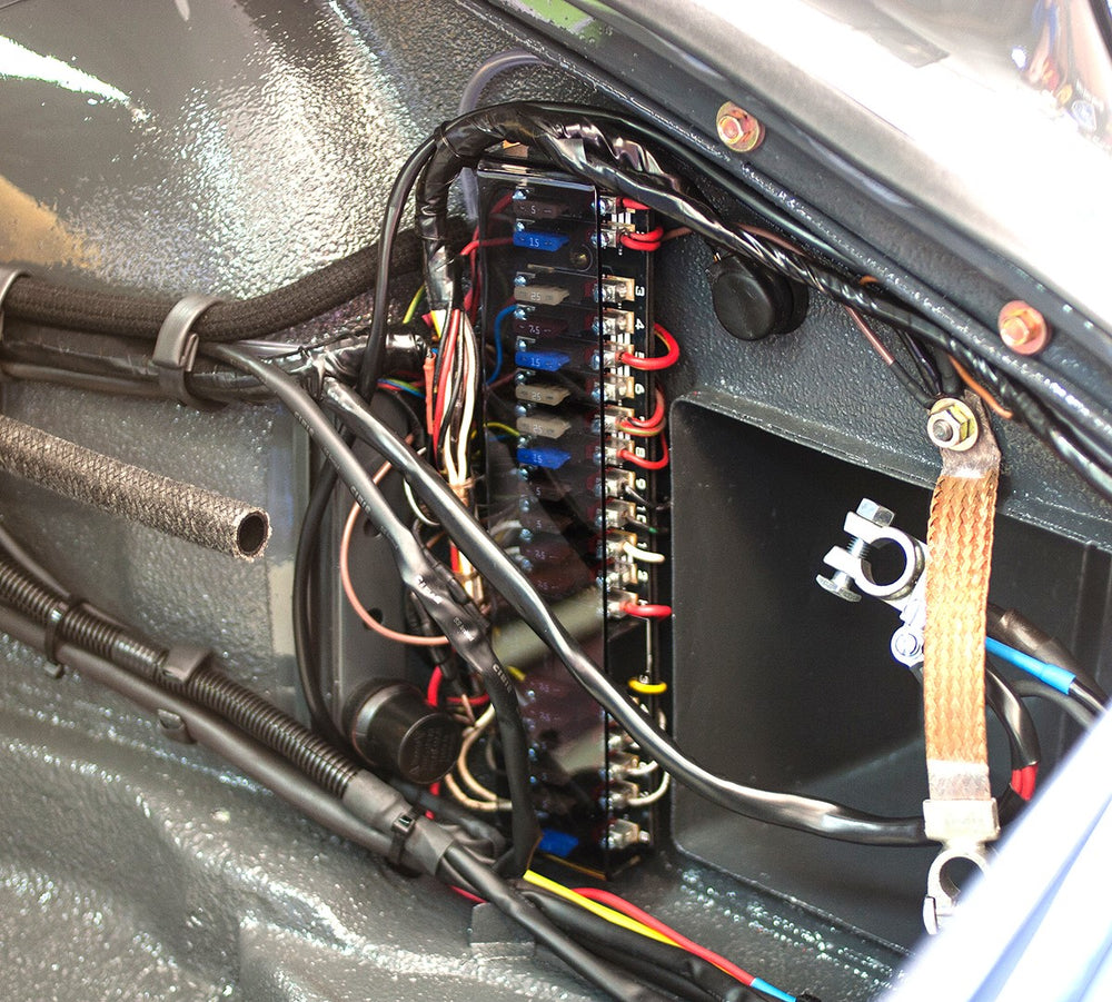 An upgraded fuse panel installed in the front trunk of a classic Porsche sports car